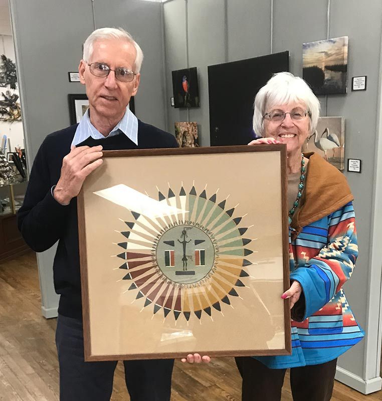 Jim Riley, past president of the Art League of North Florida/Gateway Art Gallery, receives one of the donations of the Harter Trust from Rose Pavey, Administrator. This piece is a Navajo sand painting and will be in the Exhibit.