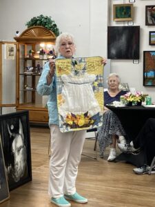 Teddy Pruett shows ALNF members and guests one of the handmade quilts from her "Lullabies on Linen" collection (photo by Sheila Carr)